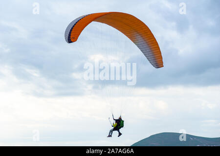 Gudauri, Kazbegi, Georgien: Menschen Paragliding durch den Teufel Tal im Kaukasus. Im Hintergrund die bunten Gipfel von Mount Kazbek Stockfoto