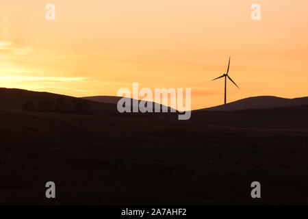 Drumahastie (südlich von Barrhill, Ayrshire, Schottland, UK) Windmühle Sonnenuntergang Silhouette, Teil eines großen Windparks an Land. Stockfoto