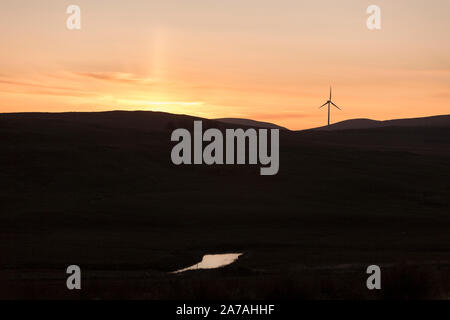 Drumahastie (südlich von Barrhill, Ayrshire, Schottland, UK) Windmühle Sonnenuntergang Silhouette, Teil eines großen Windparks an Land. Stockfoto