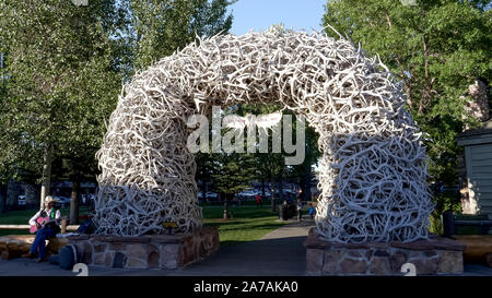 JACKSON HOLE, Wyoming, USA - 17. AUGUST 2017: Ein Schuss ein strassenmusikant sitzen neben einem geweih Arch in Jackson Hole Stockfoto