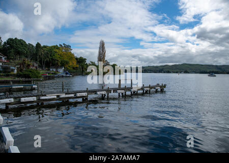 Alten hölzernen Steg ragt in der Bucht am Lake Tarawera an einem sonnigen Bewölkter Tag Stockfoto