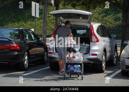 Arlington, VA/USA - 22. September 2019: Kaukasischer Mann legt Lebensmittel weg in seinen Koffer als seine Tochter starrt auf die Kamera Stockfoto