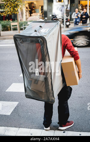 Barcelona, Spanien - 17.November 2017: Der junge Mann, der auf seinem Rücken ein extra großes Sehen - durch Lieferung Tasche mit mehrere Amazon Boxen Stockfoto