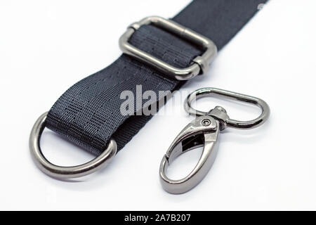 Nähen von Beschlägen für die Herstellung von Taschen und Rucksäcken. Karabiner, halben Ring und Höhenversteller in dunklen Nickel Farbe auf weißem Hintergrund. Schwarzes Band für Stockfoto