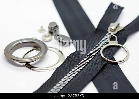 Clip aus Metall an der Kordel in dunklem Silber. Schelle für eine Schnur über eine Feder mit einem Loch. Black Fabric-basierten Reißverschluss und Ösen. Zubehör für die Manufact Stockfoto