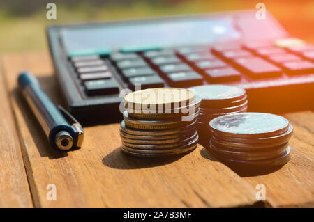 Geld aus verschiedenen Ländern im Hintergrund, Taschenrechner, Kugelschreiber und Münzen sind auf Sie, Blick von oben auf die Münzen und Stift Stockfoto