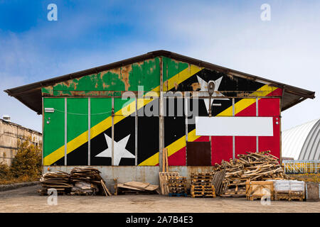 Nahaufnahme der nationalen Flagge von Saint Kitts und Nevis auf dem Metall Wand einer großen Lagerhalle malte die geschlossenen Gebiet an einem Sommertag. Die anhand von quantitativen Simulatio Stockfoto