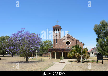 Die katholische Kirche mit einem blühenden Jacaranda Tree (Jacaranda mimosifolia) in der kleinen ländlichen Stadt Chinchilla, Queensland, Queensland, Australien Stockfoto