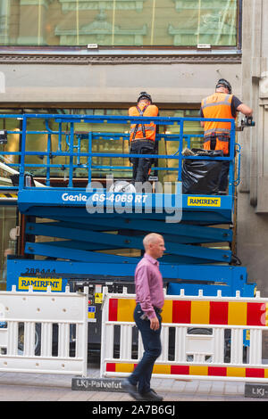Männer bei der Arbeit und ein Passant in rosa Hemd in der Aleksanterinkatu Straße in Helsinki Finnland Stockfoto