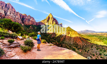 Frau Wanderer den Sonnenaufgang über dem Watchman Peak im Zion National Park, Utah, USA, während eines frühen Morgens Wanderung auf der Wächter Trail. Stockfoto