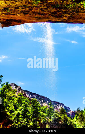 Ein kleiner Wasserfall über die Klippen überragen den Trail auf den unteren Emerald Pool im Zion National Park, Utah, United States fließende Stockfoto