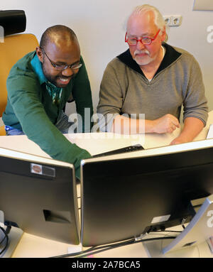 Dummerstorf, Deutschland. 30 Okt, 2019. Julien Nguinkal Alban (L-R) und Ronald Brunner die Arbeit an Computern am Institut für Genomforschung an der Leibniz Institut für Biologie der Tiere (FBN). Zusammen mit anderen Forschern vom Institut, Sie haben jetzt das Genom der Zander zum ersten Mal aufgeklärt. Es besteht aus 24 Chromosomen und, mit ca. 1 Milliarden Basenpaare, ist etwa ein Drittel der Größe eines mammalian Genome. Die Bildung des Genoms ist wichtig für die Haltung von Zander in der Aquakultur. Quelle: Bernd Wüstneck/dpa-Zentralbild/dpa/Alamy leben Nachrichten Stockfoto