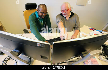 Dummerstorf, Deutschland. 30 Okt, 2019. Julien Nguinkal Alban (L-R) und Ronald Brunner die Arbeit an Computern am Institut für Genomforschung an der Leibniz Institut für Biologie der Tiere (FBN). Zusammen mit anderen Forschern vom Institut, Sie haben jetzt das Genom der Zander zum ersten Mal aufgeklärt. Es besteht aus 24 Chromosomen und, mit ca. 1 Milliarden Basenpaare, ist etwa ein Drittel der Größe eines mammalian Genome. Die Bildung des Genoms ist wichtig für die Haltung von Zander in der Aquakultur. Quelle: Bernd Wüstneck/dpa-Zentralbild/dpa/Alamy leben Nachrichten Stockfoto