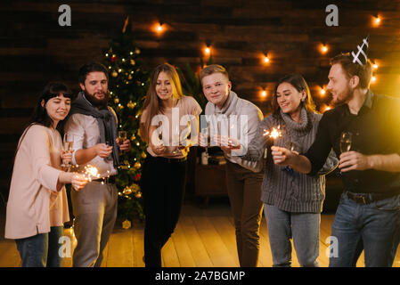 Fröhliche Freunde posieren mit Champagner Gläser und mit bengalischen Lichter Stockfoto