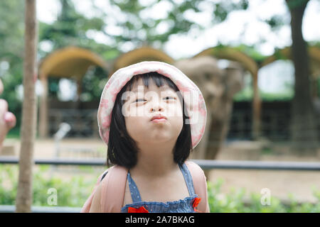 Süße kleine Mädchen Tiere im Zoo an warmen und sonnigen Sommer Tag beobachten. Kinder beobachten zoo Tiere durch die Fenster. Zeit mit der Familie im Zoo. Stockfoto