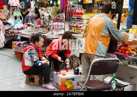 Die drei weiblichen stall Besitzer in kurzen gemeinsamen Mittagessen auf dem Karton als Tabelle durch ihre Geschäfte am Namdaemun Markt, Seoul, Südkorea. Stockfoto