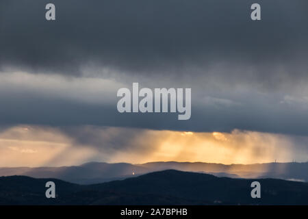 Sonnenstrahlen kommen über Berge in Umbrien (Italien) mit schönen goldenen Stunden Farben. Stockfoto