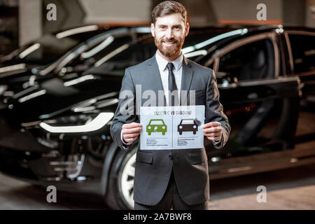 Elegante Sales Consultant zeigt eine Zeichnung zum Thema Umweltfreundliche Elektroautos, Verkauf von Fahrzeugen im Autohaus Stockfoto