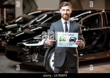 Elegante Sales Consultant zeigt eine Zeichnung zum Thema Umweltfreundliche Elektroautos, Verkauf von Fahrzeugen im Autohaus Stockfoto