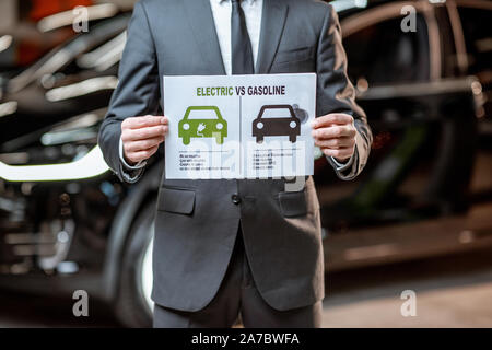 Elegante Sales Consultant zeigt eine Zeichnung zum Thema Umweltfreundliche Elektroautos, Verkauf von Fahrzeugen im Autohaus Stockfoto