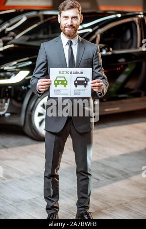 Elegante Sales Consultant zeigt eine Zeichnung zum Thema Umweltfreundliche Elektroautos, Verkauf von Fahrzeugen im Autohaus Stockfoto