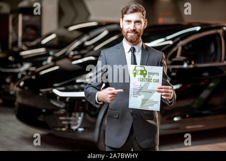 Elegante Sales Consultant zeigt eine Zeichnung zum Thema Umweltfreundliche Elektroautos, Verkauf von Fahrzeugen im Autohaus Stockfoto