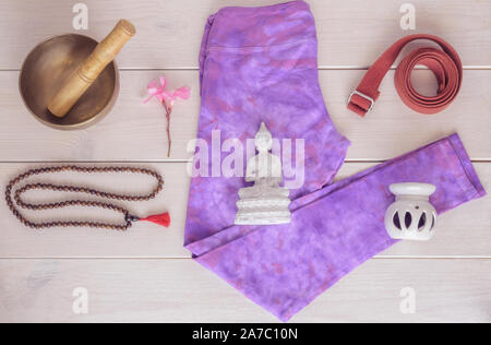 Yoga Hosen, Aromalampe, Statue Buddha, Klangschale, Holz- mala Perlen und Yoga Gurt auf Holz- Hintergrund. Wichtiges Zubehör für die Praxis yo Stockfoto