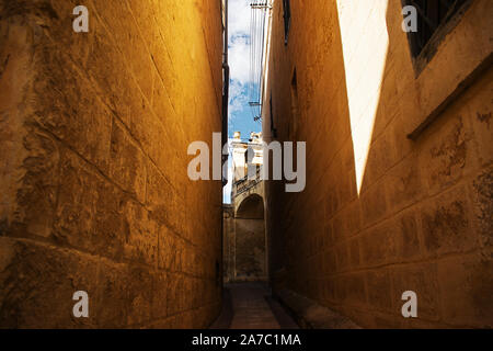 Schmale Gasse in Attard, Malta. Alte Mauern aus Kalkstein in einer engen Straße in Attard, Malta. Stockfoto