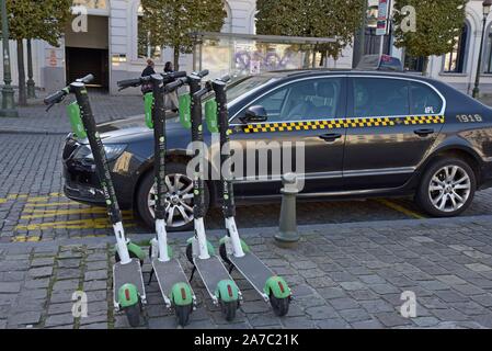 Eine Reihe von Kalk S dockless elektrische Motorroller mieten Neben einem Taxistand in Place de Luxemburg, Brüssel, Belgien geparkt Stockfoto