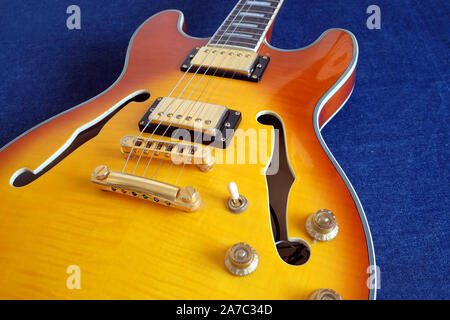 Vintage semi-Hohlkörper jazz E-Gitarre mit goldenen Pickups, Elektronik Knöpfe und Metall Zubehör auf Blue Jeans Hintergrund Nahaufnahme Stockfoto