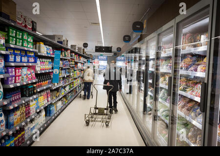 Bilder zu einem co-op Lebensmitteln lagern. Ein männlicher Arbeitnehmer zieht eine Katze auf einem Gang Stockfoto