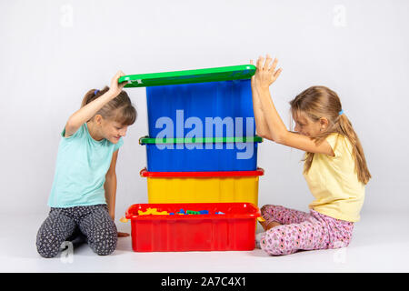 Zwei Mädchen öffnete den Deckel einer großen Box aus Kunststoff mit Spielzeug, und nach innen schauen Stockfoto