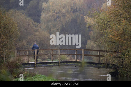 Eine Person, die die Brücke über den Fluss Itchen im Ovington, Hampshire. Stockfoto