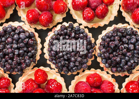 Frische Sommer Heidelbeeren nd Erdbeeren in einem Törtchen auf einer hölzernen Hintergrund. Stockfoto