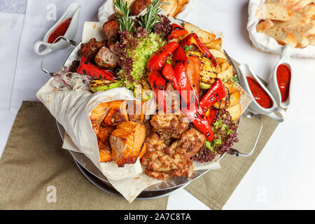 Mixed Grill Fleisch, gebratenes Gemüse und gegrillter Lachs Fischfilets Dekoration in warmen Gericht. Verschiedene köstliche gegrillte Kebab mit Kräutern auf Platte serviert. Restaurant Menü Platte Stockfoto