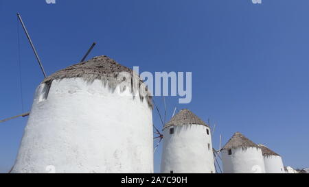 Mykonos, Griechenland: Iconic Windmühlen der Insel Mykonos bei einem Sonnenuntergang nach einem Sommer sonnigen Tag entlang der blauen Meer Stockfoto