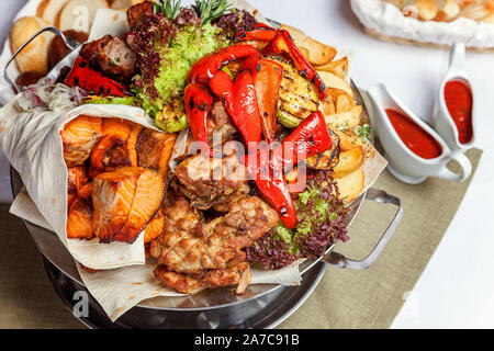 Mixed Grill Fleisch, gebratenes Gemüse und gegrillter Lachs Fischfilets Dekoration in warmen Gericht. Verschiedene köstliche gegrillte Kebab mit Kräutern auf Platte serviert. Restaurant Menü Platte Stockfoto