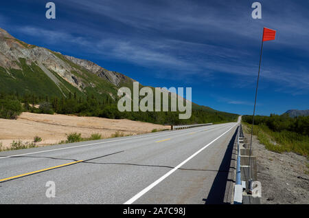 Blick entlang des Glenn Highway am Fuße des Sheep Mountain in Richtung Glennallen, mit einem roten Marker neben der Straße. Stockfoto