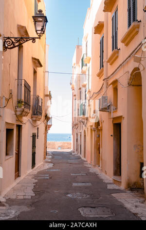 Gallipoli, Italien, 20. August 2019: Malerische Gasse in Gallipoli Downtown und das Meer vor Es Stockfoto