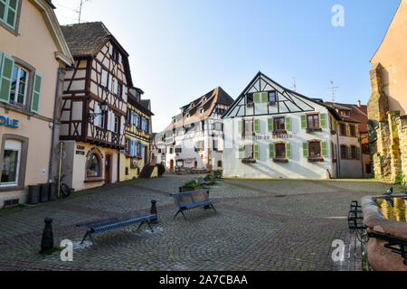 Eguisheim, Frankreich - 24. März 2019: Straße mit Fachwerkhäuser mittelalterlichen Häuser in Eguisheim Dorf an der berühmten Weinstraße im Elsass. Stockfoto