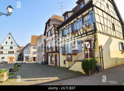 Eguisheim, Frankreich - 24. März 2019: Straße mit Fachwerkhäuser mittelalterlichen Häuser in Eguisheim Dorf an der berühmten Weinstraße im Elsass. Stockfoto