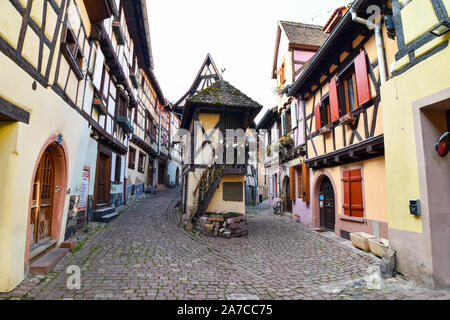 Eguisheim, Frankreich - 24. März 2019: Straße mit Fachwerkhäuser mittelalterlichen Häuser in Eguisheim Dorf an der berühmten Weinstraße im Elsass. Stockfoto