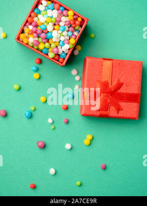 Roter Geschenkbox mit bunten Bonbons über grüne Hintergrund Stockfoto