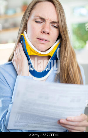 Frau zu Hause Lesen Schreiben nach Erhalt die Nackenschmerzen Stockfoto