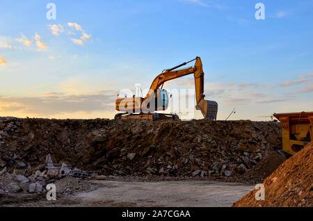 Schwerer Raupenbagger last Stein, mit alten Asphalt oder Beton Abfall in eine Mobile Backenbrecher Maschine. Die Zerkleinerung und Verarbeitung in Kies für Recycling Stockfoto