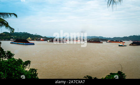 Der Verkehr von tugboat ziehen Lastkahn voller Steinkohle zu den Mahakam Fluss, Samarinda, Indonesien. Industrie und Bergbau Hintergrund Stockfoto