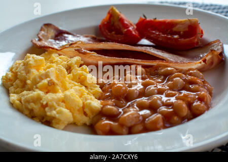 Englisches Frühstück mit gegrilltem Speck, Tomaten, Rührei und gebackene Bohnen in Tomatensoße in Spanien Stockfoto