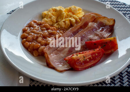 Englisches Frühstück mit gegrilltem Speck, Tomaten, Rührei und gebackene Bohnen in Tomatensoße in Spanien Stockfoto