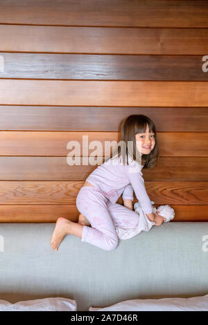 Fünf Jahre altes Mädchen kriecht auf einem Kopfteil Stockfoto