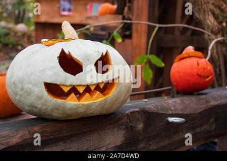 Gespenstisch weiß und orange Halloween Kürbisse, Jack O'Lantern an einem hölzernen Tisch Stockfoto